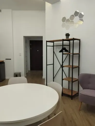 Regał metalowy z drewnianymi półkami przy białej ścianie.