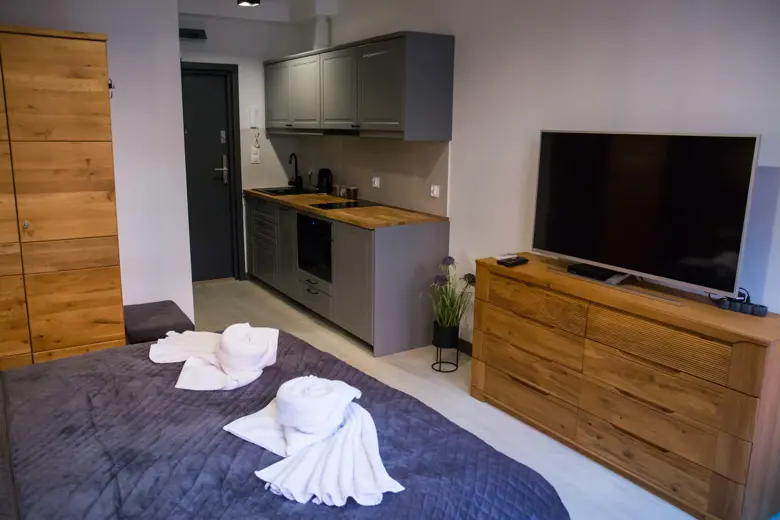 Widok z sypialni na kuchenkę i telewizor na komodzie