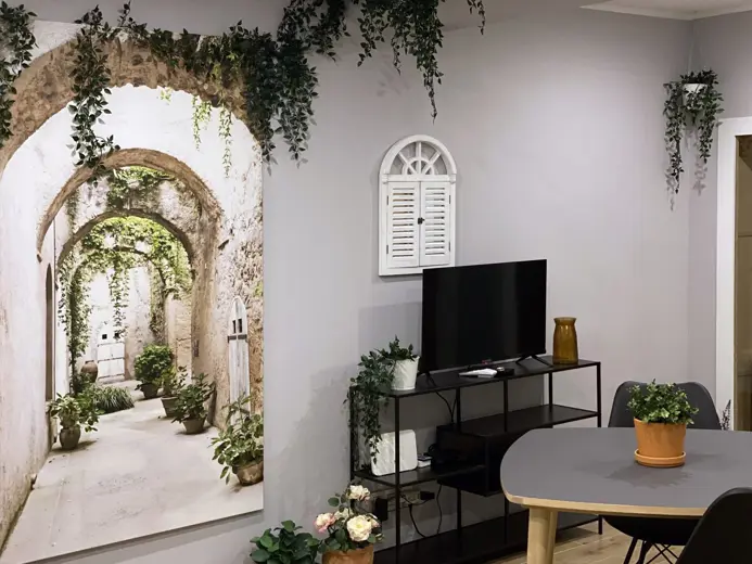 Salon z TV, stół jadalny i rośliny w doniczkach.