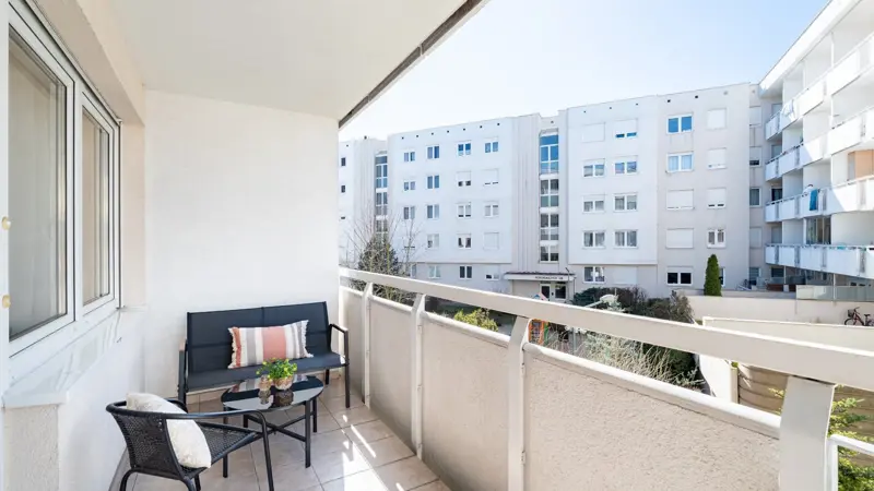 Balkon z zestawem mebli ogrodowych i widokiem na osiedle
