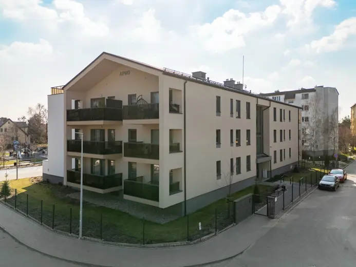 Widok na blok mieszkalny z balkonami i drogą przy budynku