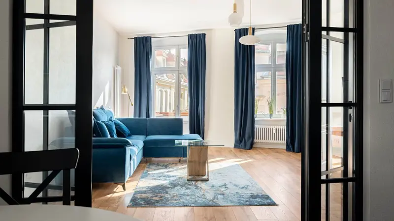 Duży, jasny salon z sofą i dużymi oknami.