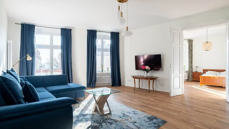 Salon z dużą sofą w kolorze granatowym i drewnianą podłogą.