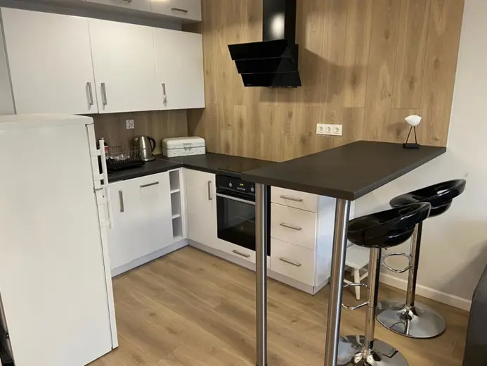 Kuchnia z drewnianą ścianą, czarna wyspa i hokery