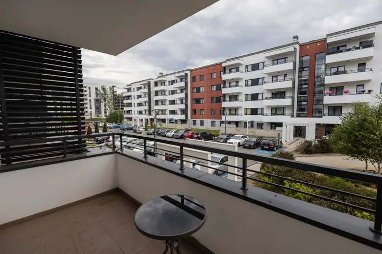 Widok na kompleks apartamentowy z parkingiem przed blokiem