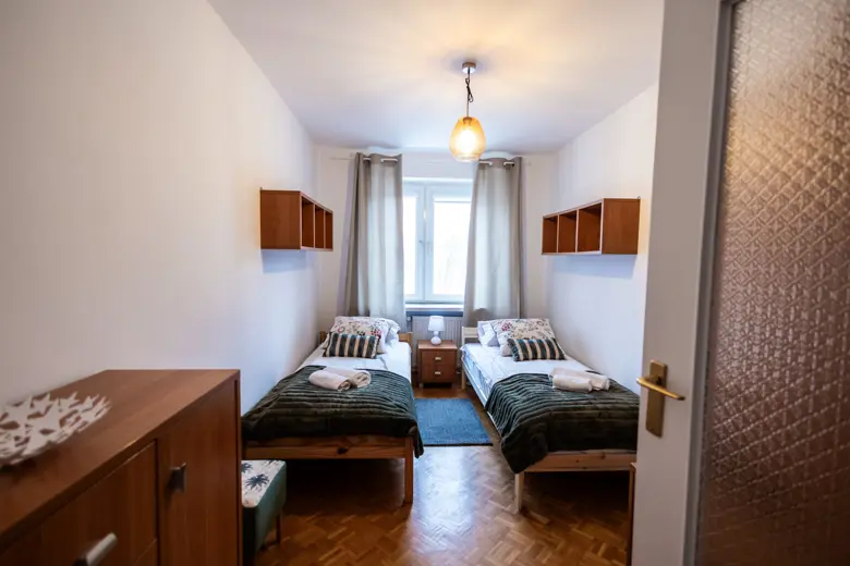 Dwa łóżka ustawione w pokoju z oknem