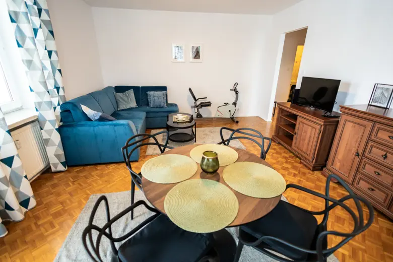 Niebieska sofa narożna w dużym salonie, stolik i meble