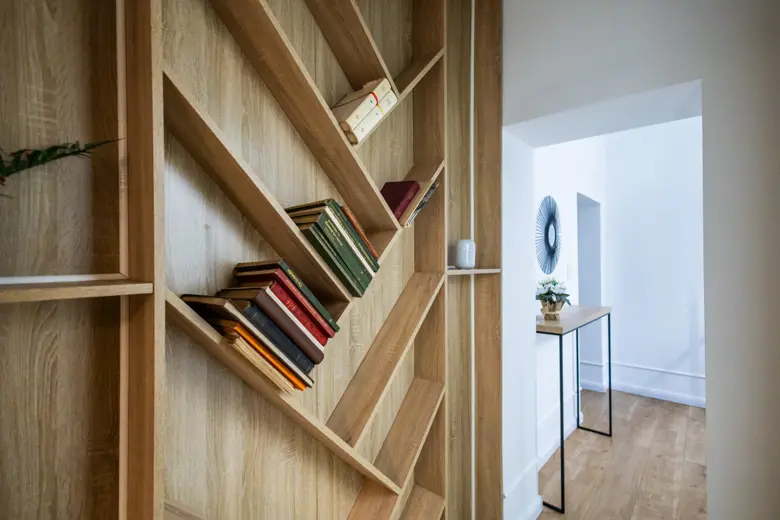 Wbudowana biblioteka z książkami na drewnianej ścianie w korytarzu.