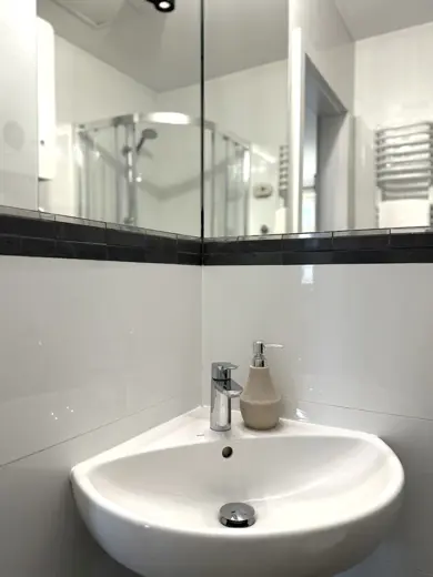 Umywalka wisząca na tle białych płytek z mydłem