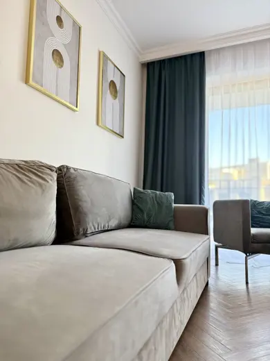 Sofa i dwa fotele przy oknie z zasłonami