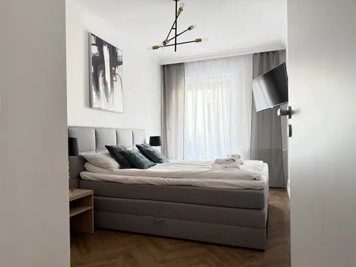 Widok na łóżko z białymi zasłonami przy oknie