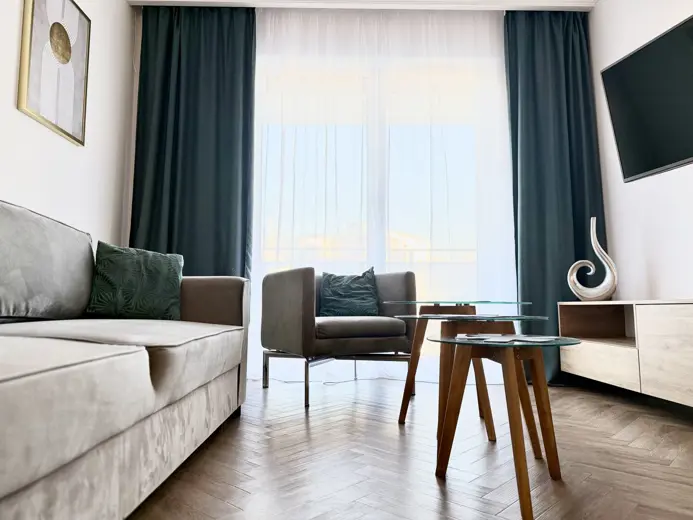 Przestronny salon z dużymi oknami i stolikami