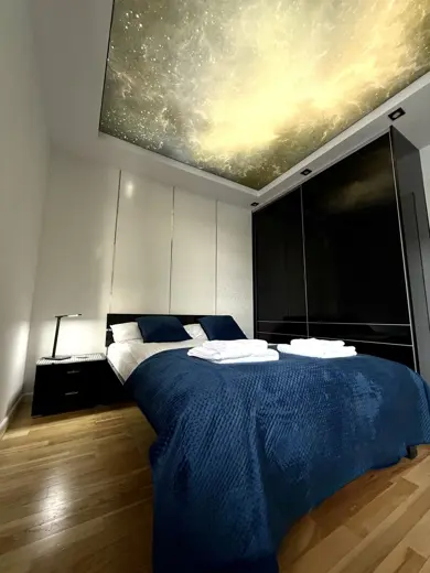 Sypialnia z ciemną zabudową, lampą i pościelą niebieską