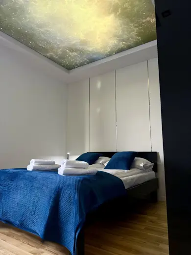 Łóżko z niebieską pościelą na białych ścianach
