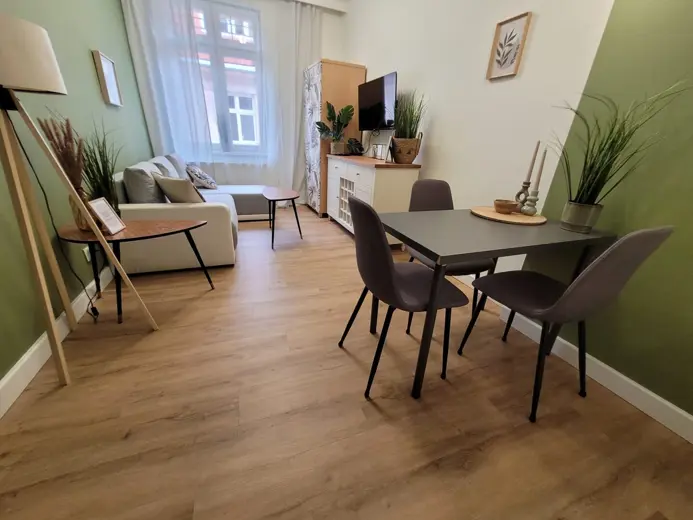 Cały salon z zieloną ścianą, sofą i stołem w jadalni