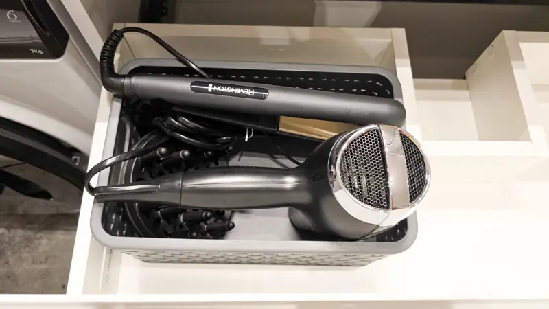 Elektronarzędzia do stylizacji i suszarka w koszyku.