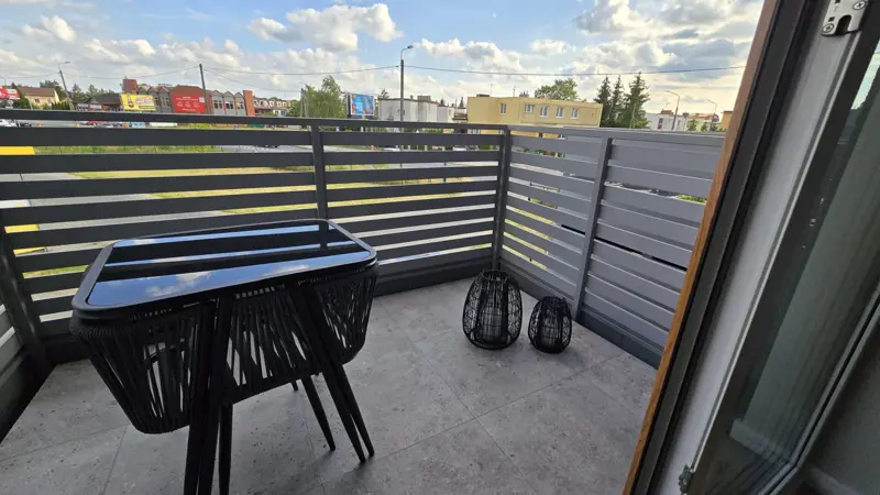 Balkon z widokiem na miasto i meblami.