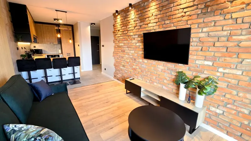 Przestronny salon z ceglastą ścianą i telewizorem.
