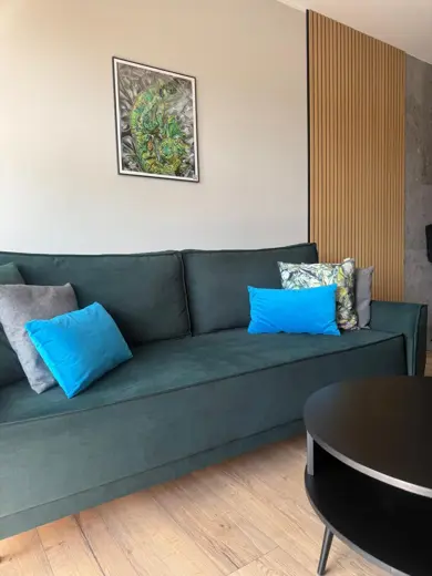 Sofa w zielonej tonacji z miękkimi poduszkami.