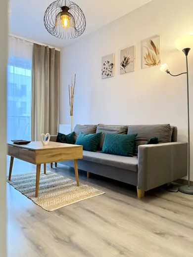 Salon z sofą, poduszkami i żyrandolem nad stołem