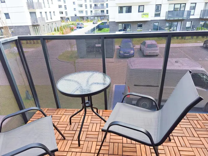 Balkon z okrągłym stolikiem i krzesłami, widok na osiedle