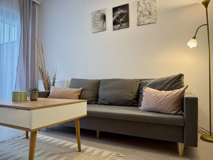 Szara sofa z kilkoma poduszkami w rogu pokoju.