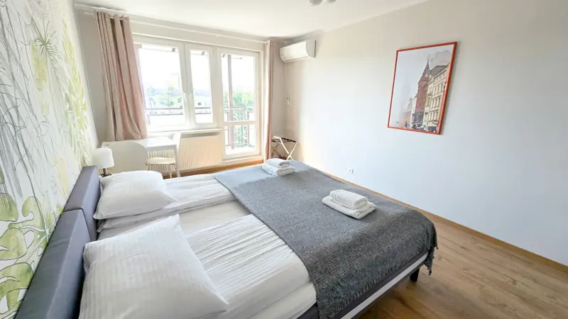 Duże okno, balkon i naturalne światło w sypialni.