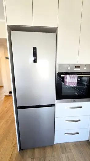 Lodówka w zabudowie obok piekarnika.