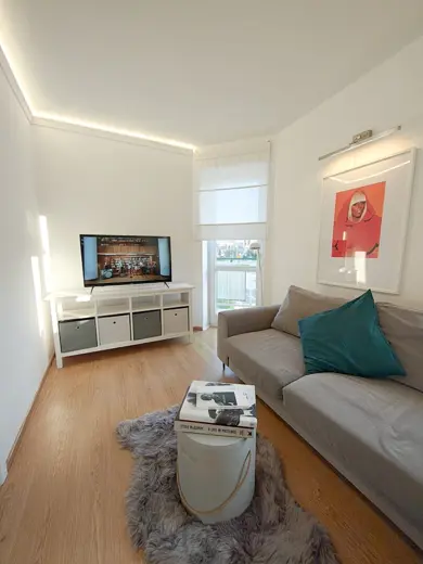 Salon z jasną sofą, niskim stolikiem i telewizorem.
