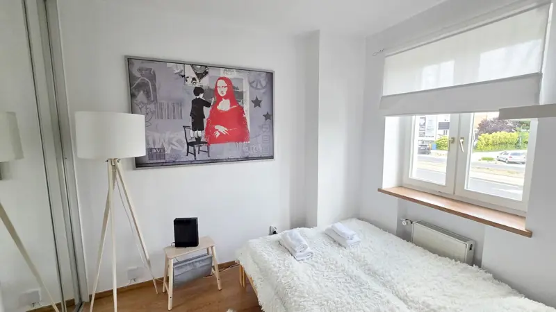 Sypialnia z grafiką na ścianie nad łóżkiem.