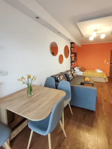 Salon z sofą, jadalnią i pomarańczową ścianą w tle