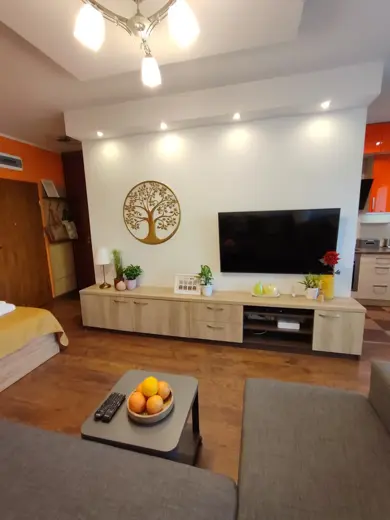 Salon z sofą, TV i jasnym oświetleniem.