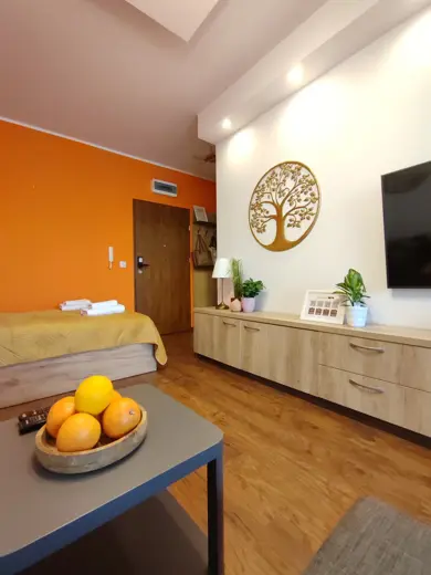 Sypialnia z pomarańczową ścianą, łóżkiem i komodą.