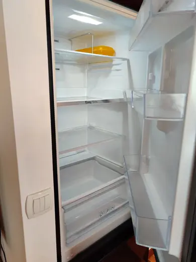 Wnętrze lodówki z kilkoma półkami i dolną szufladą
