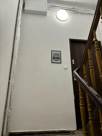Korytarz z białymi ścianami, schody drewniane i lampa.