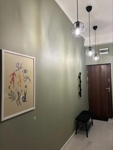 Korytarz z zielono-szarą ścianą, lampami i obrazem