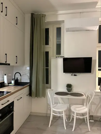 Jadalnia z dwoma krzesłami przy wydzielonej kuchni i TV