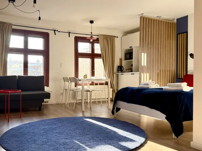 Salon z sofą, stołem jadalnym przy oknach i zasłonami