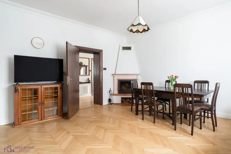Salon z drewnianą szafką pod telewizor i kominkiem.