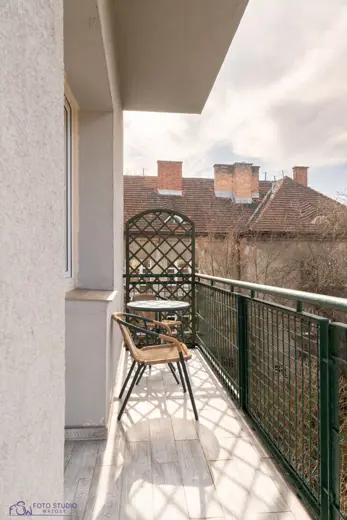 Balkon z widokiem na miasto, stolik i krzesła.
