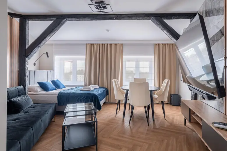 Duży salon z jadalnią, stołem i krzesłami przy oknach
