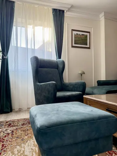 Salon z granatowo-niebieskim fotelem przy oknie.