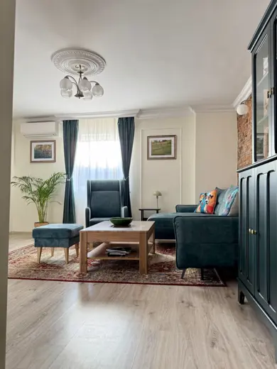 Salon z sofą, fotelem i oknem, przytulny układ.