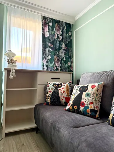 Sofa z jasnym materiałem, w towarzystwie barwnych poduszek.