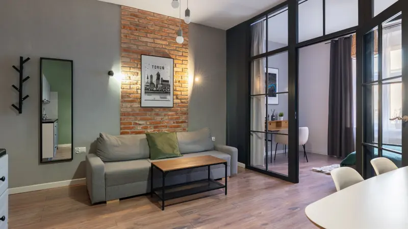 Salon z ceglaną ścianą, sofa i szklane drzwi