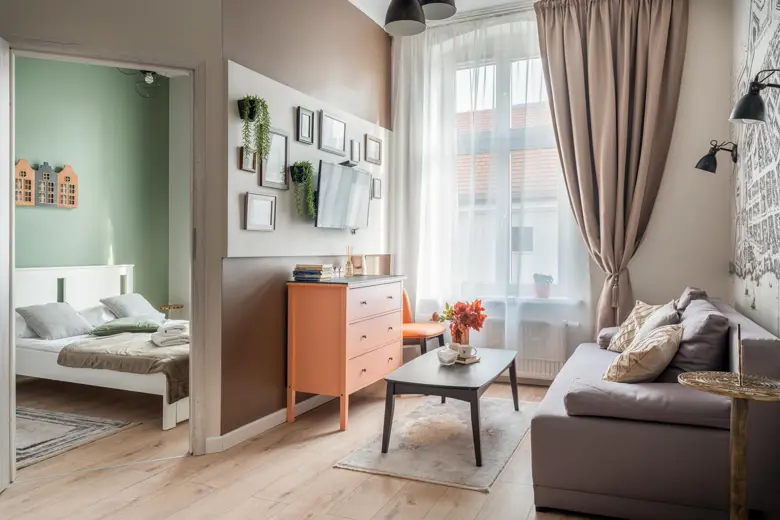 Salon z szarą sofą, jasnym panelem i oknem