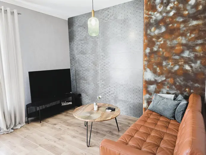 Salon z szarą ścianą i pomarańczową sofą.