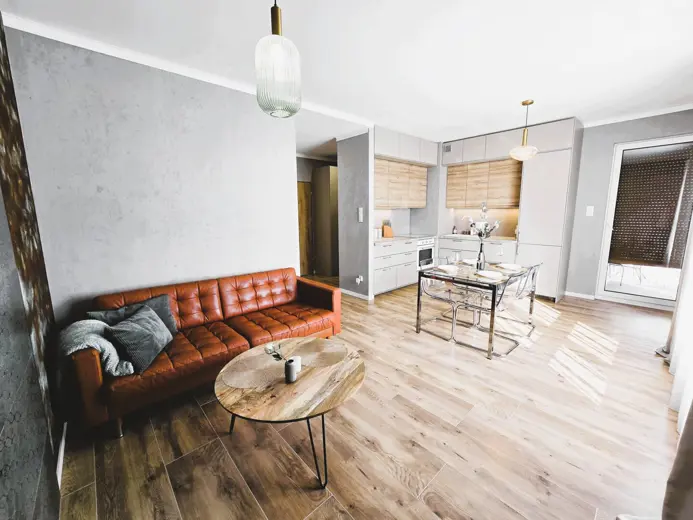 Przestronny salon z dużymi oknami i stołem z krzesłami.