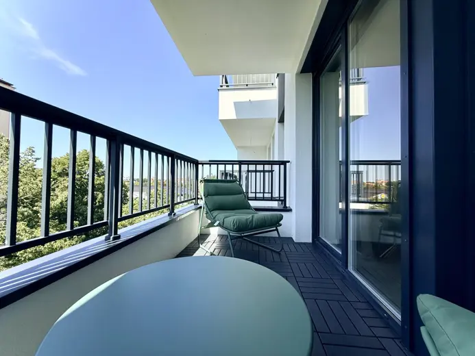 Balkon z zielonym fotelu i okrągłym stołem, widok na zieleń