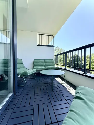 Balkon z sofą i okrągłym stolikiem, duże drzwi balkonowe